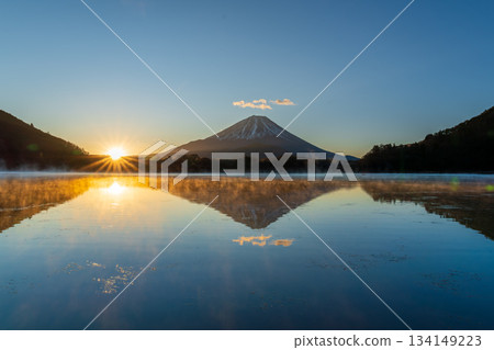 Mount Fuji and the morning sun reflected on the lake surface from the shore of Lake Shoji Mount Fuji and the morning sun reflected on the lake surface from the shore of Lake Shoji 134149223