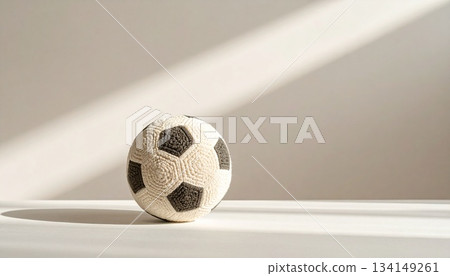 A hand-knitted wool soccer ball with its finely woven yarn is placed against a warm caramel matte background. 134149261