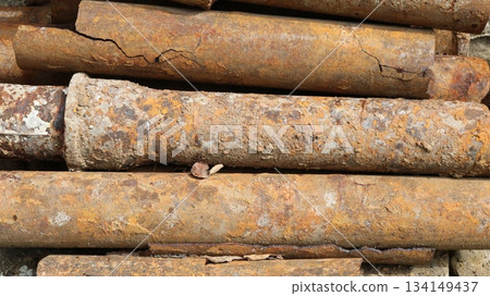 Old used rusty iron pipes with cracks and growths lying in a pile, background industrial rough texture, waste water supply system pipes, replacement of old unusable water supply system Old used rusty iron pipes with cracks and growths lying in a pile, background industrial rough texture, waste water supply system pipes, replacement of old unusable water supply system 134149437