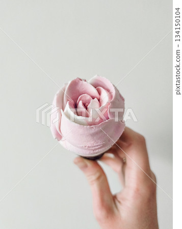Hand holding rose shaped ice cream against gray background valentines mothers day 134150104