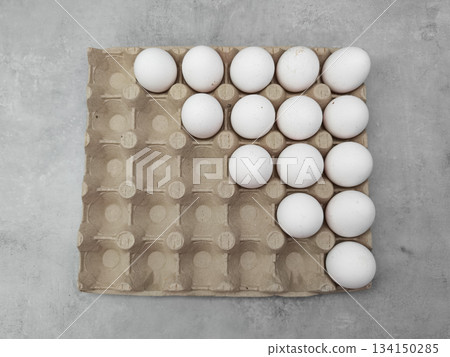 White eggs forming an arrow shape in carton on gray background easter 134150285