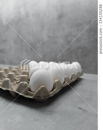 White eggs resting in carton on gray table for easter breakfast White eggs resting in carton on gray table for easter breakfast 134150286