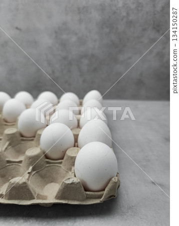 White eggs resting in cardboard container on gray surface easter 134150287