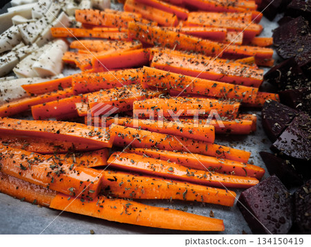 Seasoned carrot sticks with beetroot and parsnip ready for roasting healthy dinner snacks 134150419