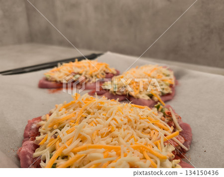 Preparing stuffed Turkey thigh steaks with grated cheese and spices gray background Preparing stuffed Turkey thigh steaks with grated cheese and spices gray background 134150436