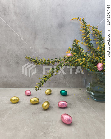 Chocolate easter eggs scattered on a table with mimosa flowers in prague copy space gray background Chocolate easter eggs scattered on a table with mimosa flowers in prague copy space gray background 134150444