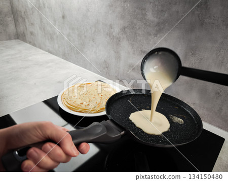 Cook pouring pancake batter into frying pan on induction cooker in prague for shrove tuesday, maslenitsa or breakfast Cook pouring pancake batter into frying pan on induction cooker in prague for shrove tuesday, maslenitsa or breakfast 134150480