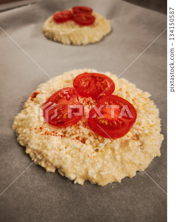 Mini cottage cheese pizzas topped with fresh tomatoes and spices, baking on parchment paper for a delightful valentine's breakfast in prague 134150587