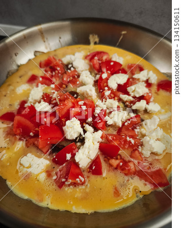 Sizzling omelette with tomatoes, goat cheese, olives preparing delectable breakfast for romantic morning Sizzling omelette with tomatoes, goat cheese, olives preparing delectable breakfast for romantic morning 134150611