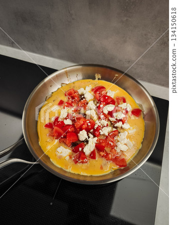 Cooking cheesy omelette with ripe tomatoes in skillet, romantic morning meal for couples Cooking cheesy omelette with ripe tomatoes in skillet, romantic morning meal for couples 134150618