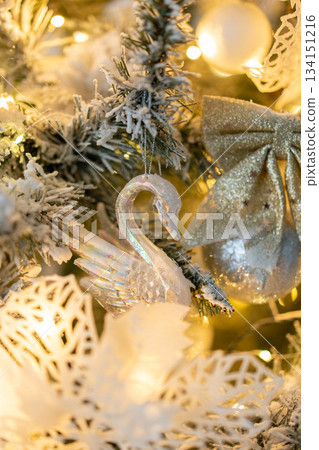 Snow-covered Christmas tree with white swan decorations close-up with warm lights. Decorations for the New Year and Christmas Snow-covered Christmas tree with white swan decorations close-up with warm lights. Decorations for the New Year and Christmas 134151216