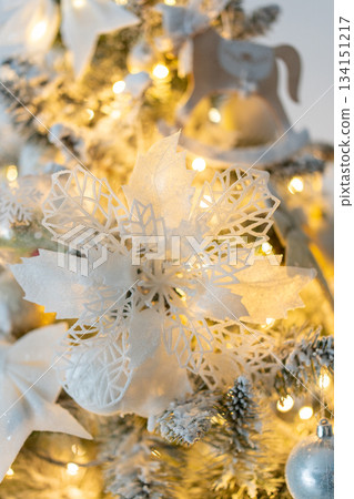 Snow-covered Christmas tree with white snowflake decorations close-up with warm lights. Decorations for the New Year and Christmas Snow-covered Christmas tree with white snowflake decorations close-up with warm lights. Decorations for the New Year and Christmas 134151217