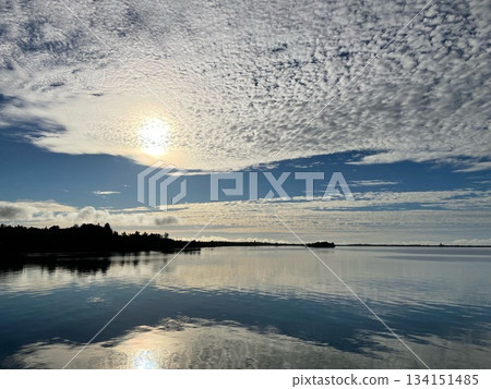 Spreading clouds and light reflected on the calm water 134151485