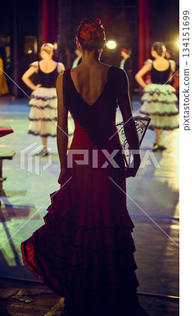 Dancer in layered red dress observing stage from side wing. Dancer in layered red dress observing stage from side wing. 134151699