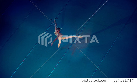 Ballerina executing extended leap across lit stage. Ballerina executing extended leap across lit stage. 134151714