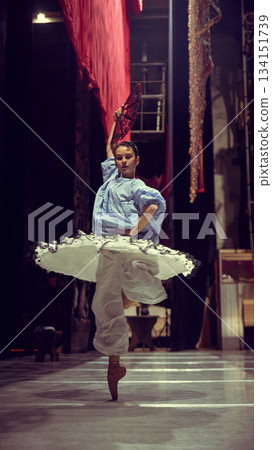 Ballerina spinning with fan in dramatic backstage rehearsal space 134151739