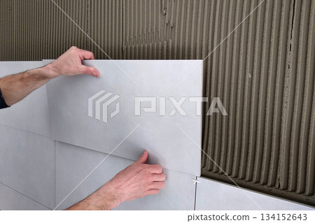 Worker hands putting ceramic tiles on the wall. Worker hands putting ceramic tiles on the wall. 134152643