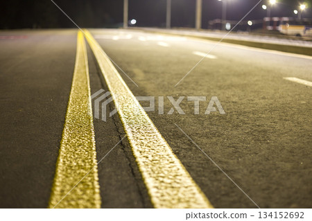 Wide bright yellow street marking sign line along modern wide smooth empty asphalt highway stretching to horizon. Speed, safety, comfortable journey and professional road building concept. Wide bright yellow street marking sign line along modern wide smooth empty asphalt highway stretching to horizon. Speed, safety, comfortable journey and professional road building concept. 134152692