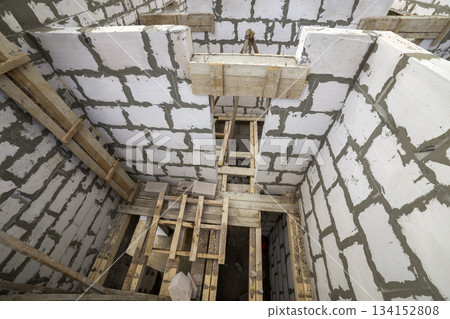 View from above of future multi stored cottage energy saving walls of large white hollow foam insulation blocks and temporary wooden scaffolding frame. Construction masonry, modern technology concept. View from above of future multi stored cottage energy saving walls of large white hollow foam insulation blocks and temporary wooden scaffolding frame. Construction masonry, modern technology concept. 134152808