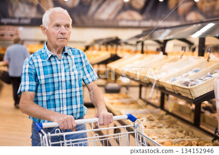 old age senor examines bakery products in the grocery section of the supermarket 134152946