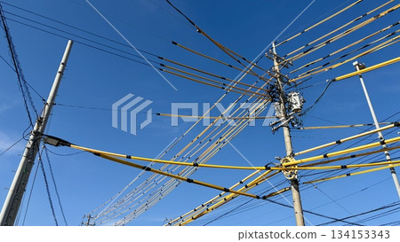 Blue sky and complex intersecting power lines and poles Blue sky and complex intersecting power lines and poles 134153343