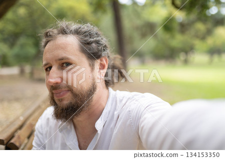 Smiling man taking selfie in green park Smiling man taking selfie in green park 134153350