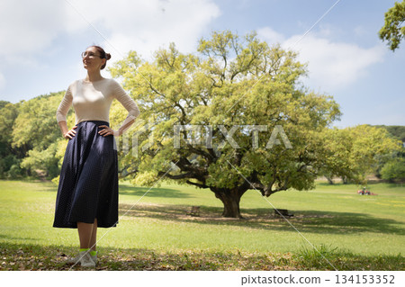 Woman standing in park looking up at sky Woman standing in park looking up at sky 134153352