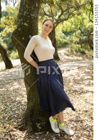 Woman smiling relaxing in natural park setting Woman smiling relaxing in natural park setting 134153353
