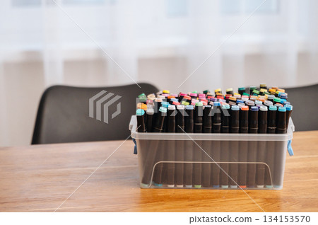 Colorful markers neatly arranged in a box on a table, ready for drawing and creative projects. 134153570