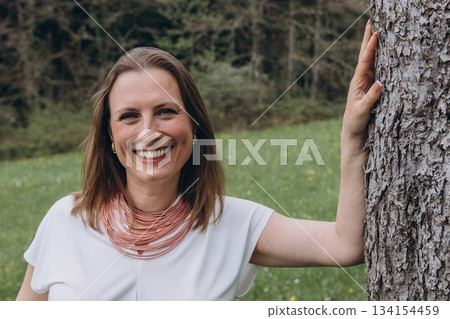 Happy middle-aged woman enjoying nature and embracing herself in spring field. Concept of self-love, female health, emotional balance, mindfulness, and positive aging 134154459
