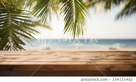 Wooden tabletop overlooking tranquil tropical beach with palm leaves, glistening bokeh sea, and clear summer sky perfect for product display or vacation-themed designs. 134155482