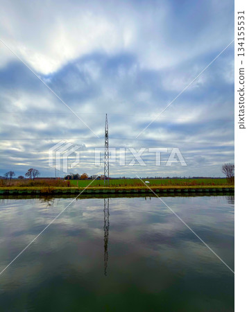 Rijkevorsel, Antwerpse Kempen, Belgium, Tall transmission structure mirrored beneath quiet canal 134155531