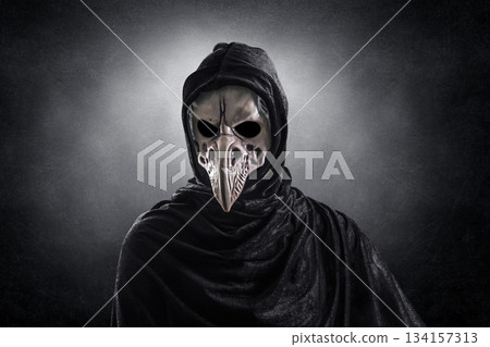 Creepy figure with animal bird skull over dark misty background 134157313