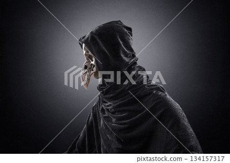 Creepy figure with animal bird skull over dark misty background 134157317