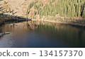 Serene lake surrounded by lush evergreen trees reflecting on water 134157370