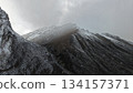 Snow-covered mountain peaks under cloudy sky with dramatic landscape 134157371