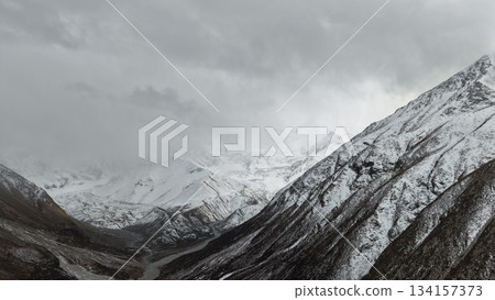 Snowy mountain landscape with dramatic clouds and valley view Snowy mountain landscape with dramatic clouds and valley view 134157373