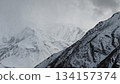 Snow-covered mountain peaks under cloudy sky with dramatic landscape 134157374