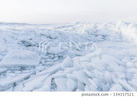 A bright icy shoreline features jagged white ice shards piled along the coast A bright icy shoreline features jagged white ice shards piled along the coast 134157521
