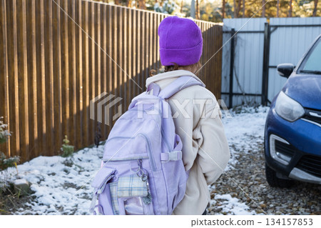 A girl goes to school in the morning with a backpack, in the yard to the car A girl goes to school in the morning with a backpack, in the yard to the car 134157853