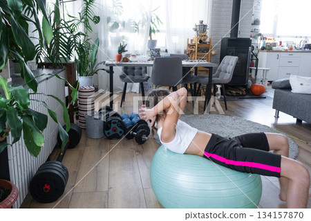 A girl performs a home workout on a fitball A girl performs a home workout on a fitball 134157870