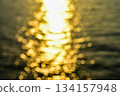 Bokeh effect of Reflection of golden sunlight on water. Sunset sea view with sparkle sunlight. Sunset light hitting on the ocean. Sunset sea background. 134157948