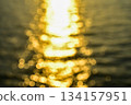 Bokeh effect of Reflection of golden sunlight on water. Sunset sea view with sparkle sunlight. Sunset light hitting on the ocean. Sunset sea background. 134157951