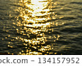 Bokeh effect of Reflection of golden sunlight on water. Sunset sea view with sparkle sunlight. Sunset light hitting on the ocean. Sunset sea background. 134157952