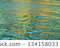 Reflection of city light on water at night. Night sea view with street light. Light hitting on the ocean.Sea background. Background of the calm water, water waves. Sea water surface. 134158033