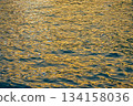 Reflection of city light on water at night. Night sea view with street light. Light hitting on the ocean.Sea background. Background of the calm water, water waves. Sea water surface. 134158036