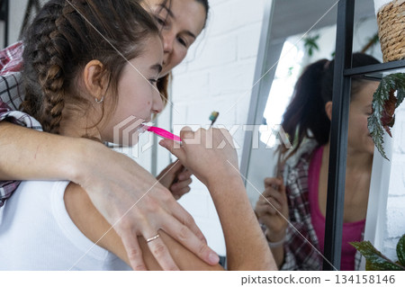 Daughter and mom brush their teeth in front of the mirror in the morning, dental hygiene Daughter and mom brush their teeth in front of the mirror in the morning, dental hygiene 134158146