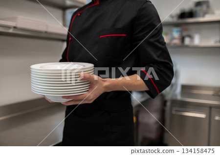 Male cook standing with dishware in culinary workspace 134158475