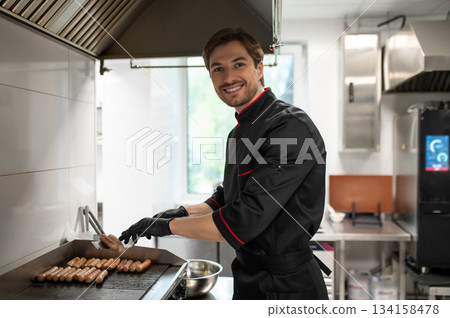Chef handling grilling process of bratwurst on griddle Chef handling grilling process of bratwurst on griddle 134158478