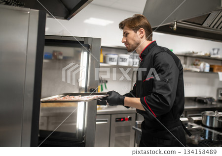 Cook preparing meat for baking in stainless steel restaurant Cook preparing meat for baking in stainless steel restaurant 134158489